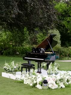 a grand piano is surrounded by flowers and greenery in the middle of a lawn