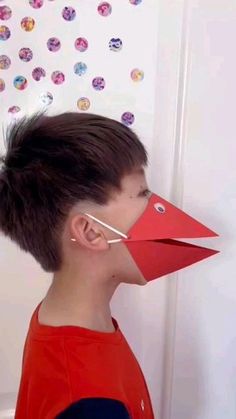 a young boy wearing a paper bird mask with his nose cut out to look like an origami bird