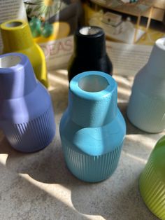 several different colored vases sitting on the ground