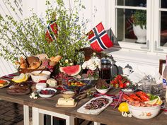 a wooden table topped with lots of food next to a flag on top of a building