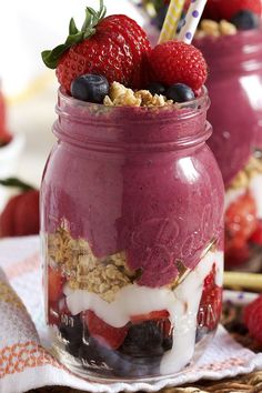 two mason jars filled with yogurt, granola and strawberries