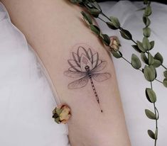 a woman's arm with a dragonfly tattoo on the left side of her body