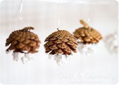 three pine cone ornaments hanging from strings