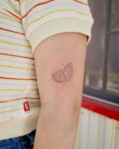 a woman with a small tattoo on her arm that has a slice of fruit on it