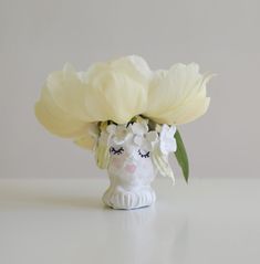 a white vase filled with flowers on top of a table