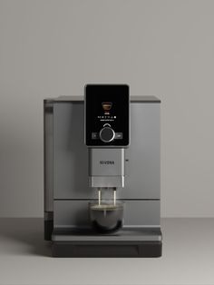 an espresso machine sitting on top of a counter next to a gray wall