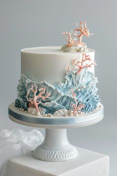 a white and blue cake with corals on top