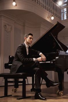 a man in a suit sitting at a piano