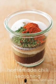 homemade chili seasoning in a glass jar on a wooden table with spices and herbs