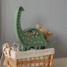 a toy dinosaur sitting in a basket next to a teddy bear