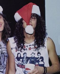 two young men wearing funny hats and drinking sodas while standing next to each other