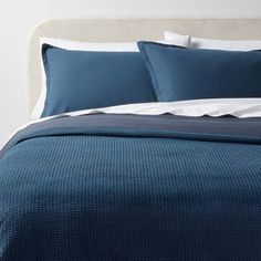 a bed with blue sheets and pillows on it