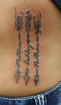 a woman's lower back tattoo with arrows and words on it, in black ink