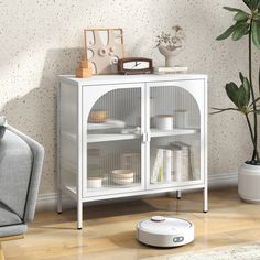 a living room with a robot on the floor next to a white cabinet and potted plant