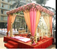 an outdoor wedding setup with flowers on the stage