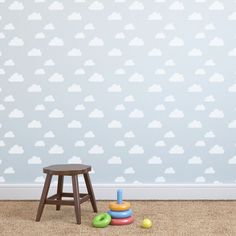 a child's room with clouds on the wall and toys in front of it