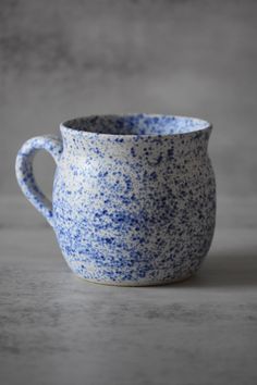 a blue and white cup sitting on top of a table next to a gray wall