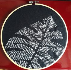 a close up of a embroidery on a piece of cloth with a plant in the center