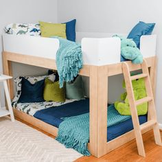 there is a bunk bed with blue and green pillows on the bottom, and a ladder to the top