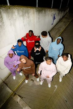 a group of people standing next to each other in front of a wall at night