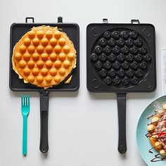 two waffles and a plate of food on a table with utensils