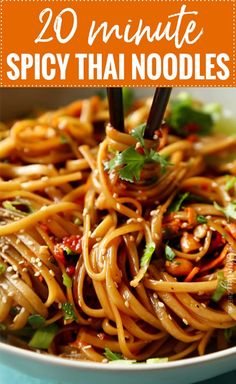 a bowl filled with noodles and vegetables on top of a blue table cloth, topped with chopsticks