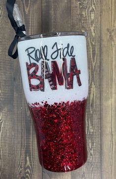 a red and white tumbler with the words roll side down on it, sitting against a wooden wall