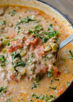 a close up of a bowl of soup with meat and vegetables in it on a wooden table