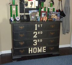 a black dresser with some pictures on it and other items sitting on top of it