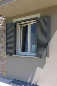 an open window on the side of a building with shutters and windowsills