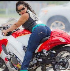 a woman riding on the back of a red and white motorcycle