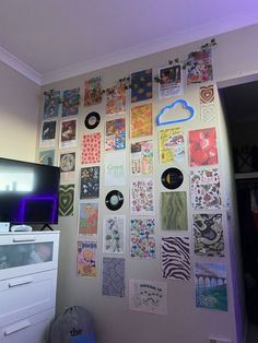 a wall covered in pictures and magnets next to a dresser with a flat screen tv on it