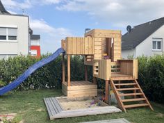 there is a wooden play structure in the yard with stairs and a slide on it