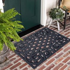 a black door mat sitting on top of a brick floor next to a green door