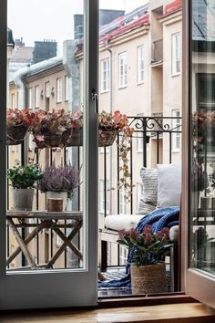 a balcony with potted plants on the windowsill and an open door leading outside