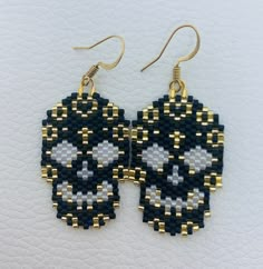 black and white beaded skull earrings with gold accents on a white leather back ground