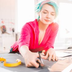 a woman cutting paper with scissors and tape