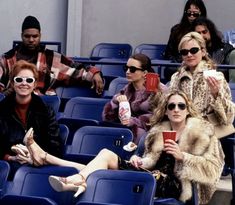 many people are sitting in the stands at a baseball game and one person is holding a drink