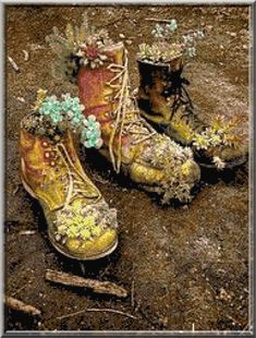 two pairs of boots with flowers on them sitting in the dirt next to each other