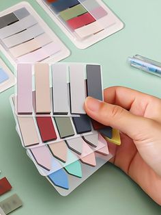 a person is holding some paint samples in their hand and there are other paints on the table