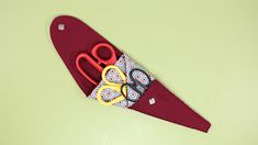 a pair of red scissors sitting on top of a piece of cloth