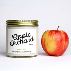 an apple sits next to a jar of aster candles on a white background with the words apple orchard printed on it