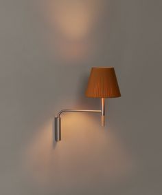 a lamp that is on the wall next to a light fixture with a brown shade