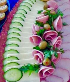 a platter with cucumbers, ham and olives on it is ready to be served