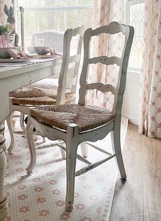 a dining room table with two chairs in front of it and a window behind it