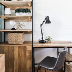 a wooden desk topped with a lamp next to a shelf filled with books and plants