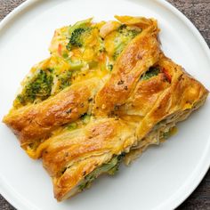 a white plate topped with two pieces of pie covered in broccoli and cheese