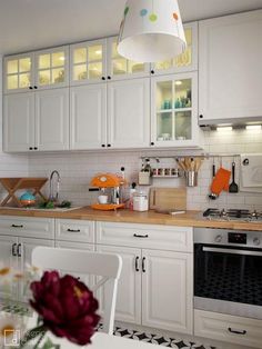 a kitchen with white cabinets and an orange flower on the table in front of it