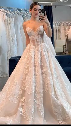 a woman taking a selfie in front of her wedding dress on the mirror while looking at it