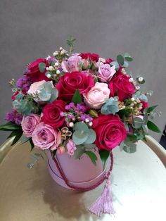 a pink box with flowers and greenery on a table